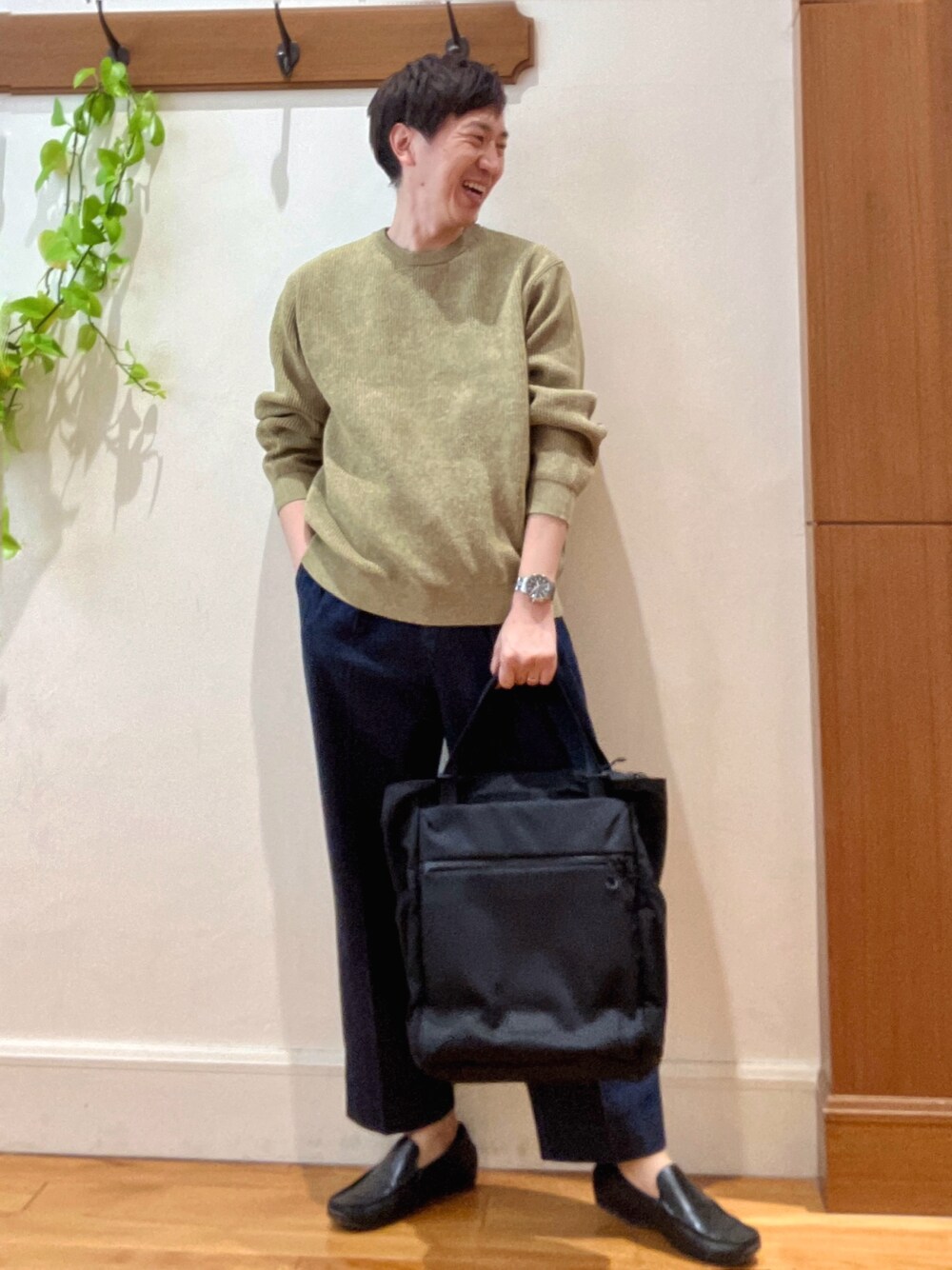 イエロー系のニット/セーター、ブルー系のデニムパンツ、ブラック系のトートバッグを着用したメンズの冬コーディネートの1枚目の写真