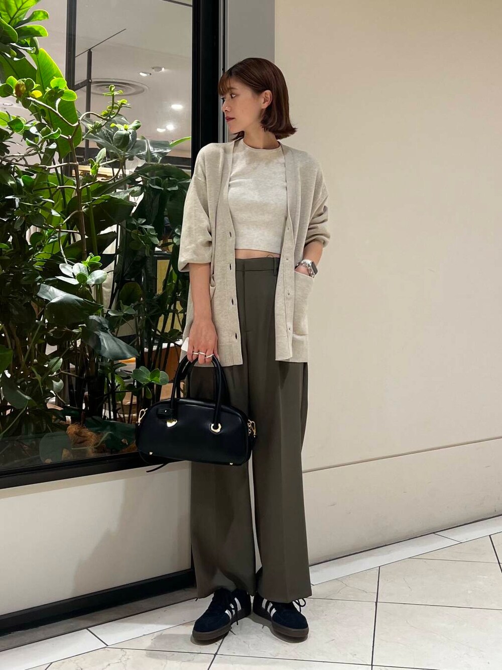 ブラック系のスニーカー、ベージュ系のカーディガン/ボレロ、ホワイト系のニット/セーターを着用したレディースの秋コーディネートの1枚目の写真