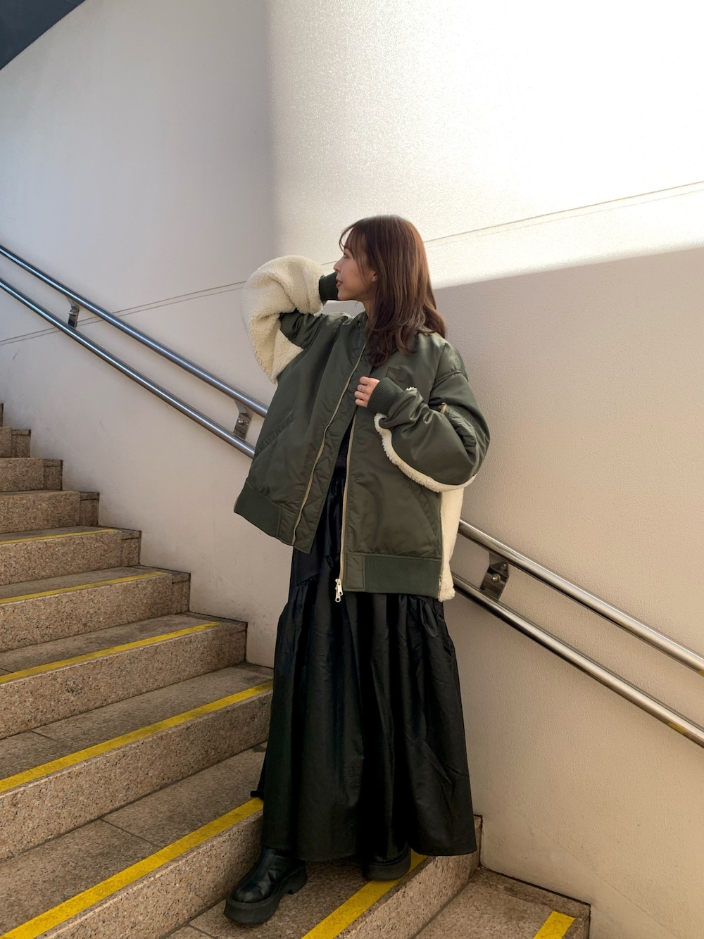 ブラック系のスカート、ブラック系のブーツ、グレー系のニット/セーターを着用したレディースの冬コーディネートの1枚目の写真