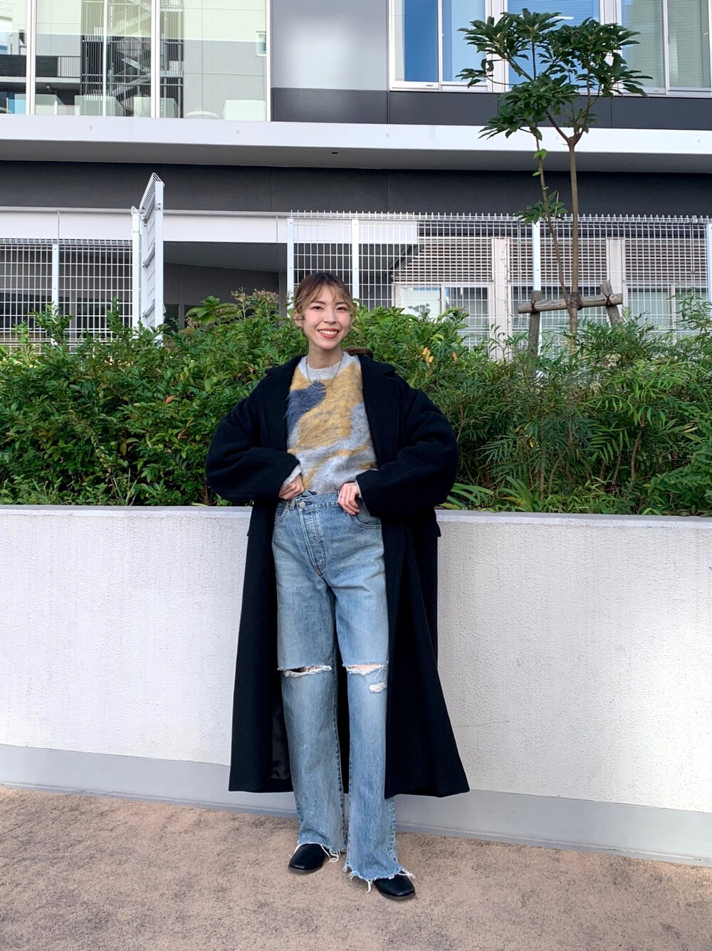 ブルー系のニット/セーター、ブラック系のチェスターコート、ブルー系のデニムパンツを着用したレディースの秋コーディネートの1枚目の写真