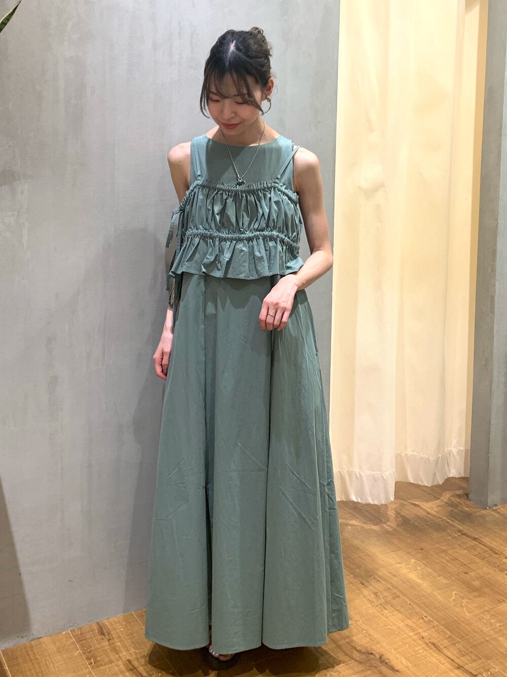 グリーン系のワンピース、ゴールド系のネックレス、シルバー系のイヤリングを着用したレディースの夏コーディネートの1枚目の写真