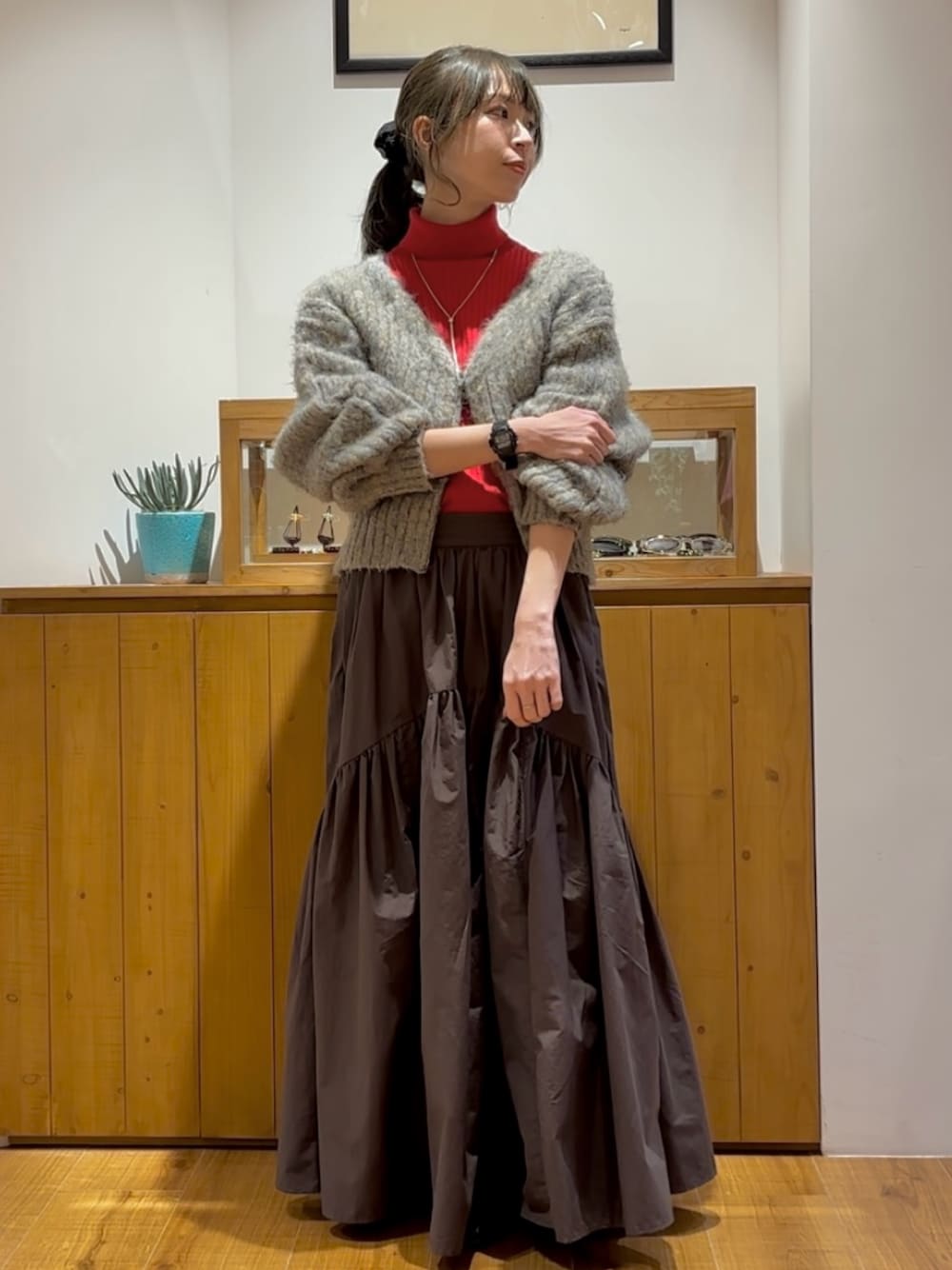 グレー系のスカート、グレー系のニット/セーター、レッド系のニット/セーターを着用したレディースの秋コーディネートの1枚目の写真