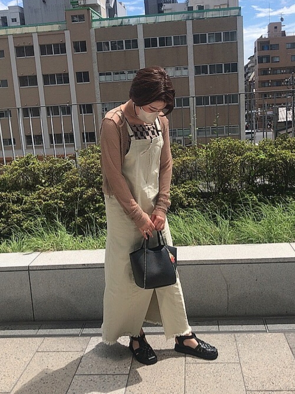 ブラック系のバッグ、ブラック系のサンダル、ベージュ系のジャンパースカートを着用したレディースの夏コーディネートの1枚目の写真