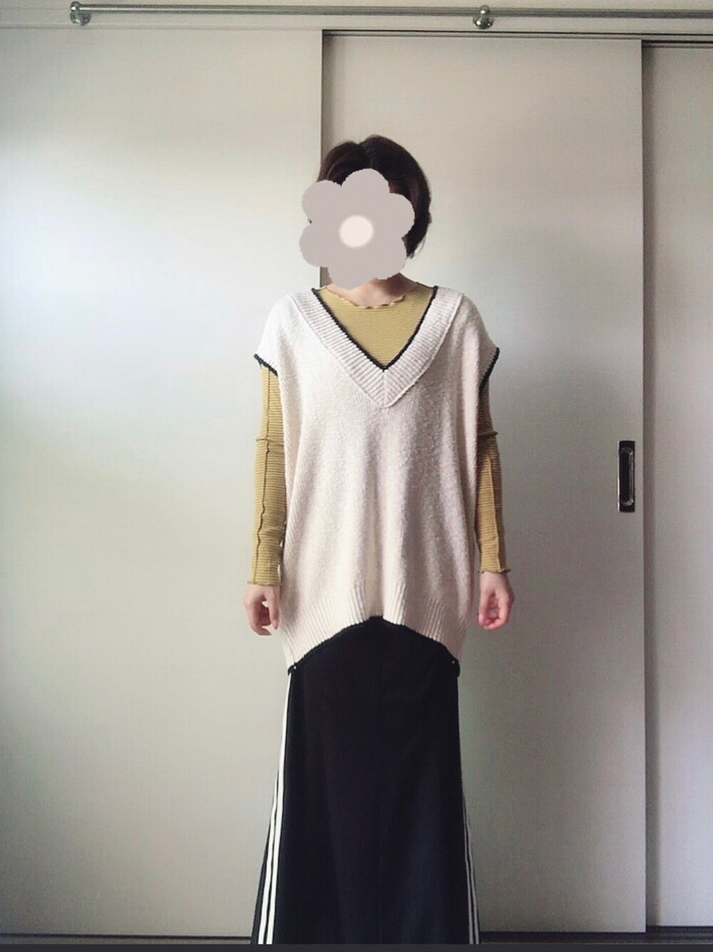 ブラック系のスカート、ホワイト系のベスト、イエロー系のTシャツ/カットソーを着用したレディースの春コーディネートの1枚目の写真