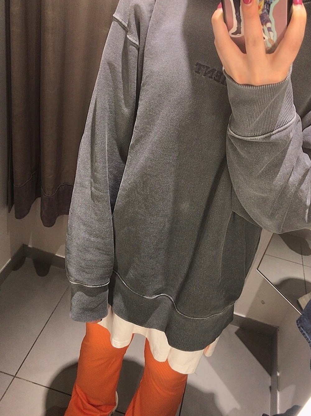 ブラック系のスウェット、ホワイト系のTシャツ/カットソー、オレンジ系のスラックスを着用したレディースの春コーディネートの1枚目の写真