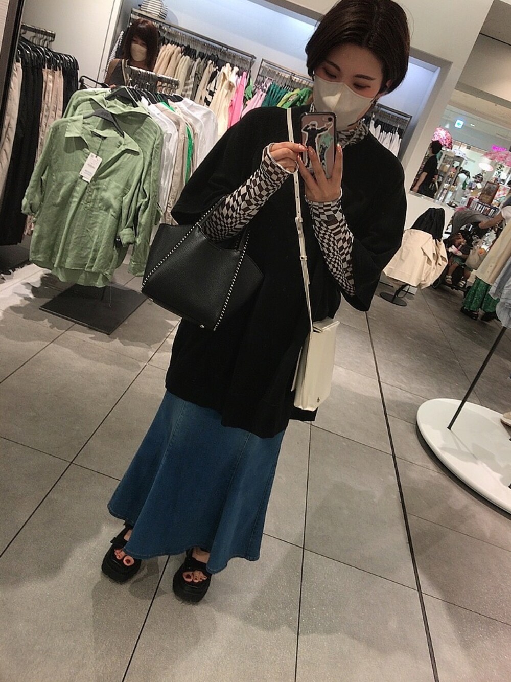 ブラック系のサンダル、ブルー系のスカート、ブラック系のTシャツ/カットソーを着用したレディースの夏コーディネートの1枚目の写真