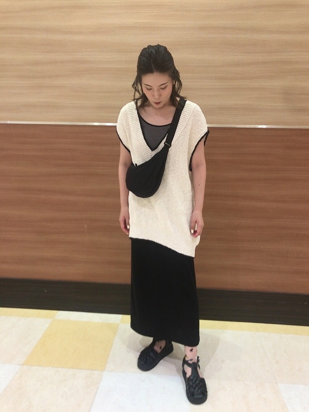 ブラック系のサンダル、ブラック系のスカート、ホワイト系のベストを着用したレディースの夏コーディネートの1枚目の写真