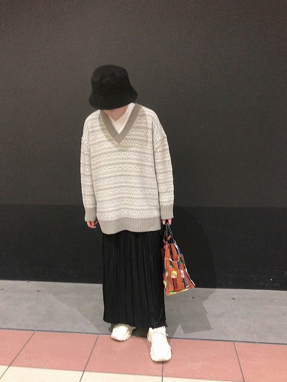 ホワイト系のスニーカー、ブラウン系のトートバッグ、ブラック系のスカートを着用したレディースの秋コーディネートの1枚目の写真