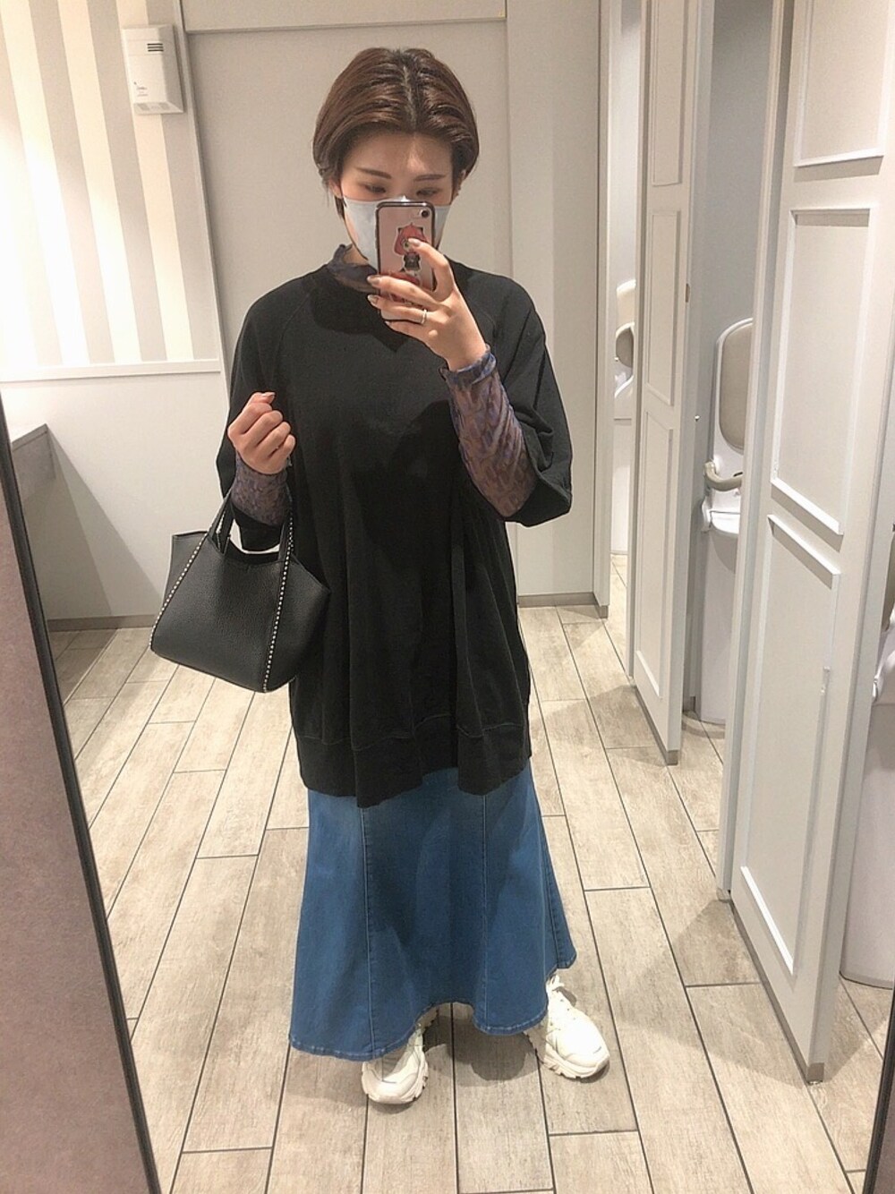 ホワイト系のスニーカー、ブルー系のスカート、ブラック系のバッグを着用したレディースの秋コーディネートの1枚目の写真