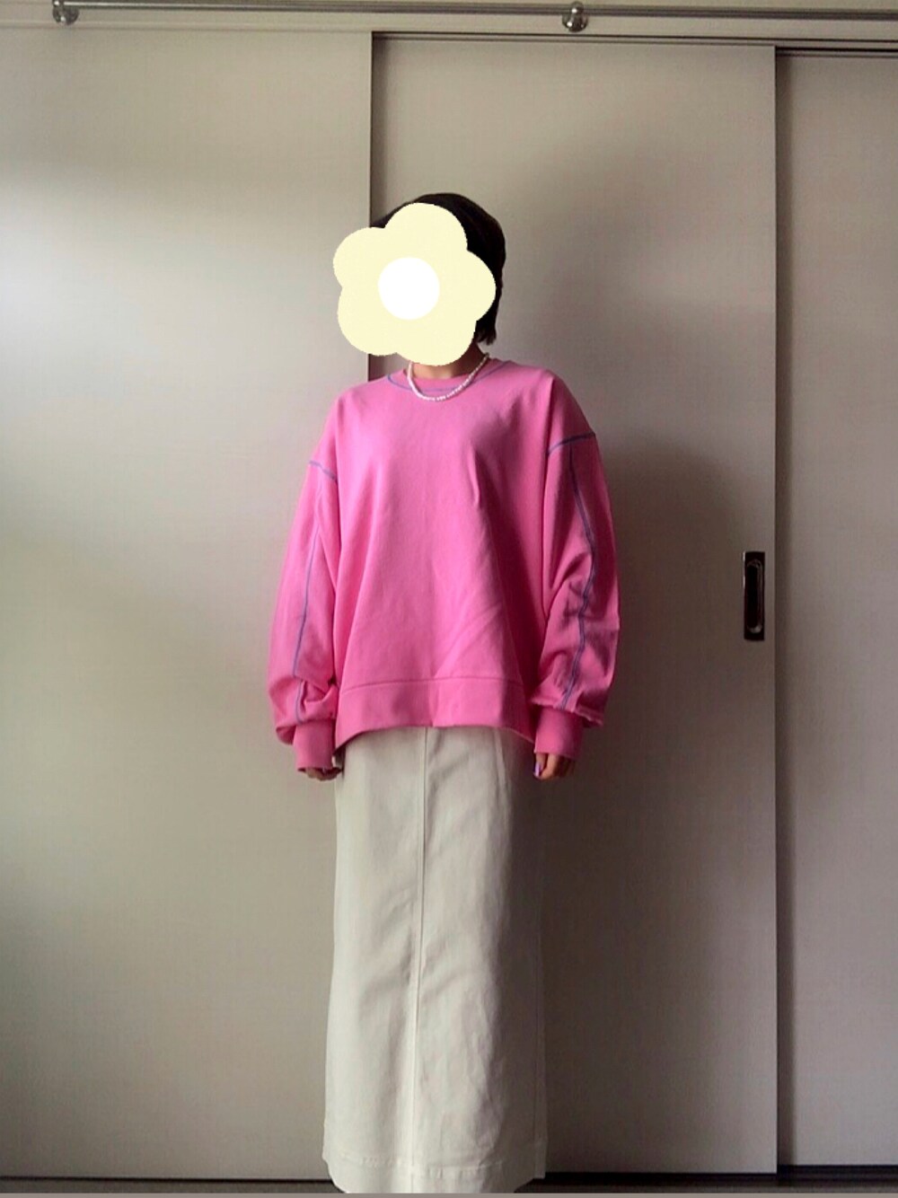 ピンク系のスウェット、ホワイト系のスカートを着用したレディースの春コーディネートの1枚目の写真