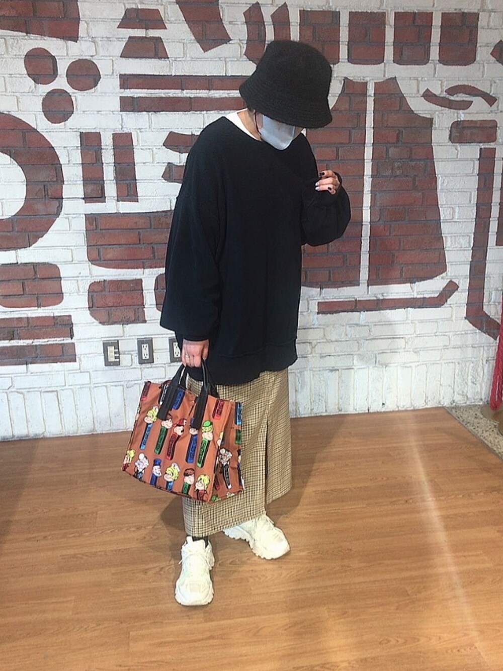 ホワイト系のスニーカー、ブラウン系のトートバッグ、ブラック系のスウェットを着用したレディースの秋コーディネートの1枚目の写真
