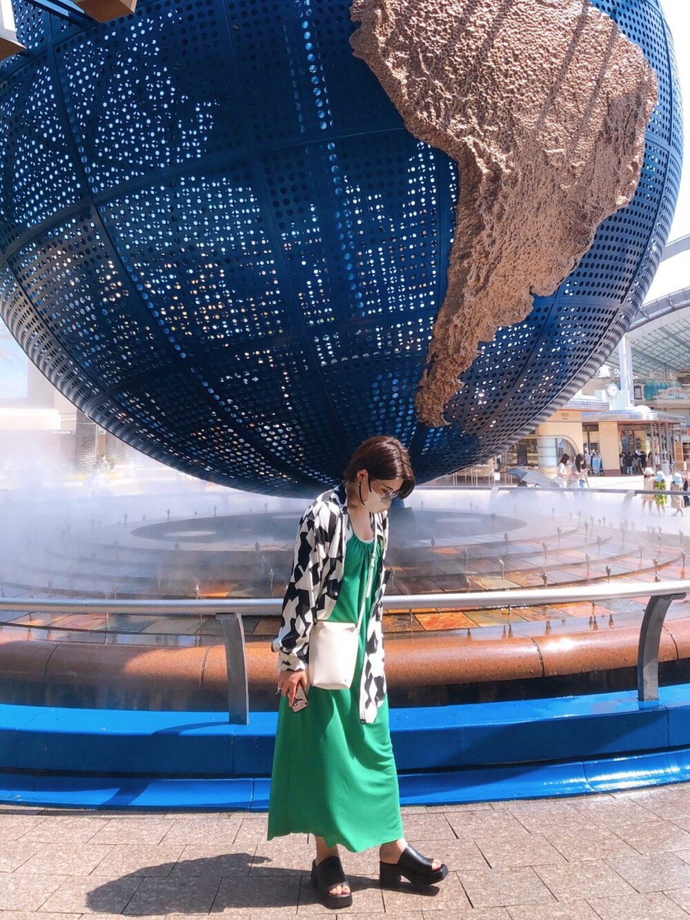 ブラック系のサンダル、グリーン系のワンピース、ホワイト系のショルダーバッグを着用したレディースの夏コーディネートの1枚目の写真