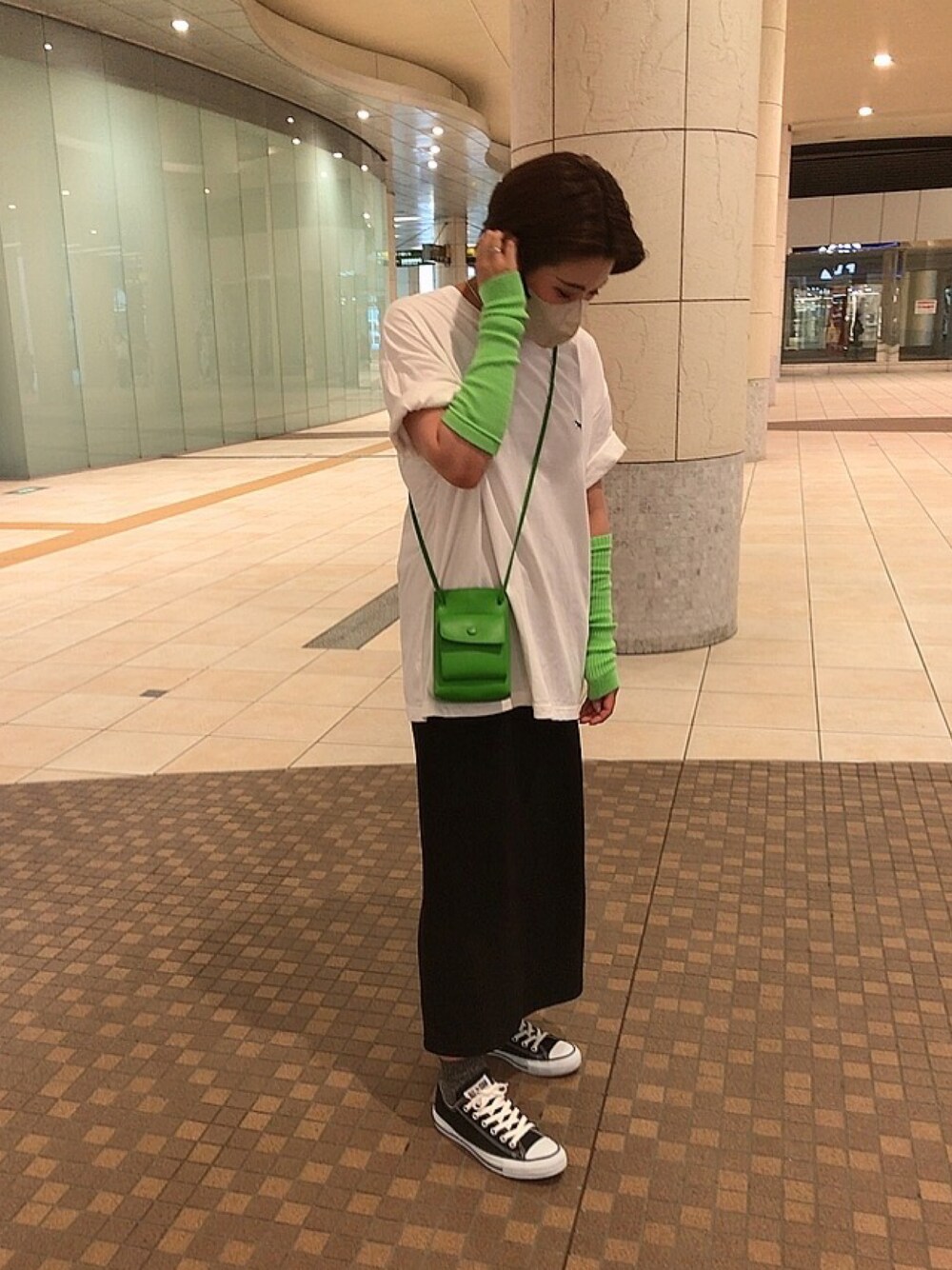 ブラック系のスニーカー、ブラック系のスカート、グリーン系のショルダーバッグを着用したレディースの夏コーディネートの1枚目の写真