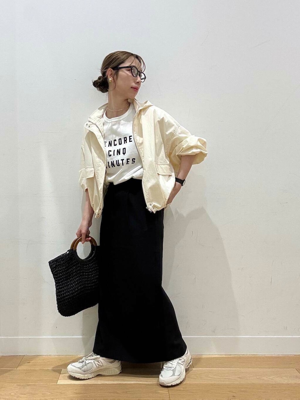 ベージュ系のスニーカー、ホワイト系のマウンテンパーカー、ブラック系のトートバッグを着用したレディースの春コーディネートの1枚目の写真