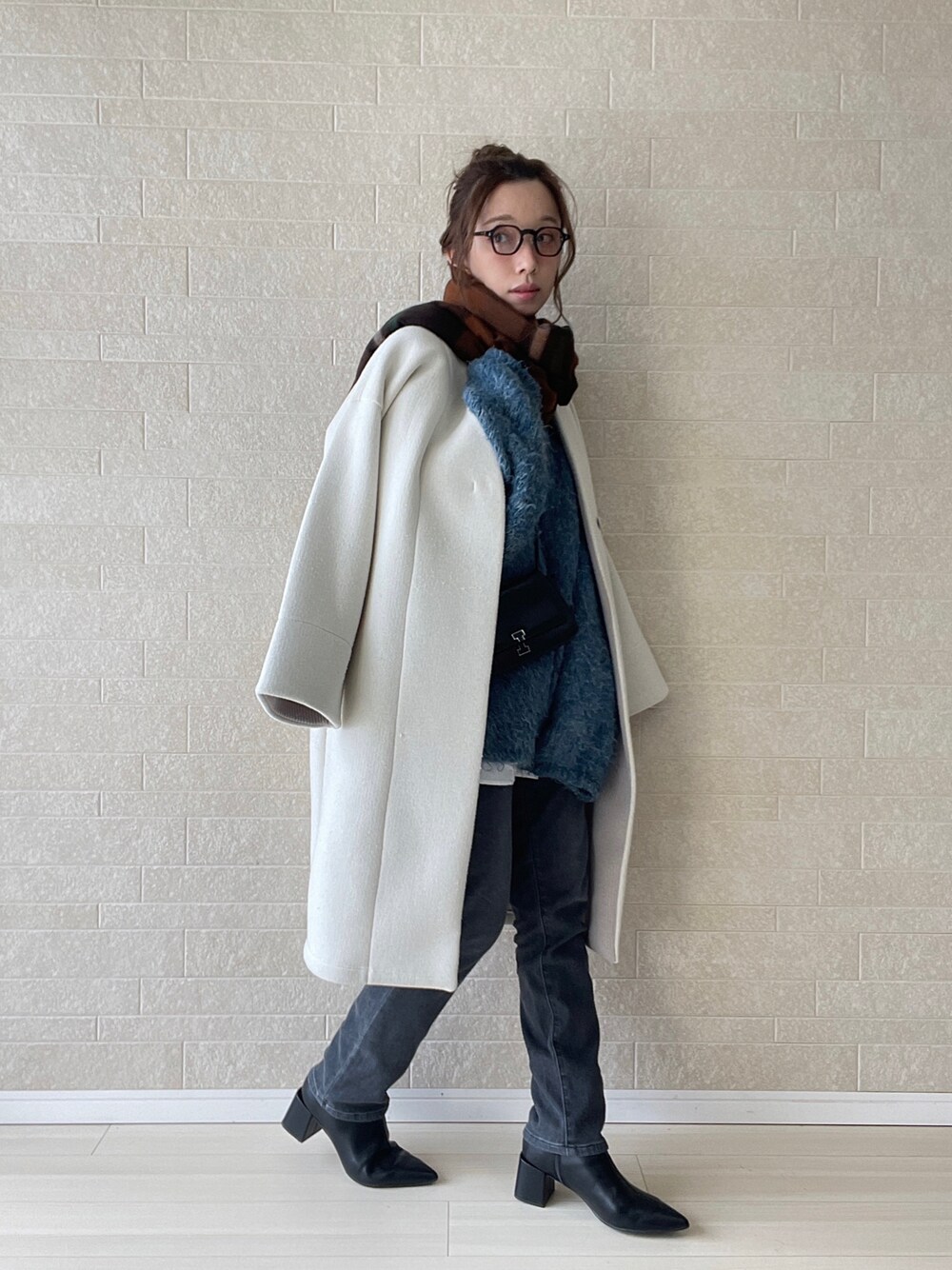 グレー系のデニムパンツ、ブラック系のブーツ、ブルー系のニット/セーターを着用したレディースの冬コーディネートの1枚目の写真