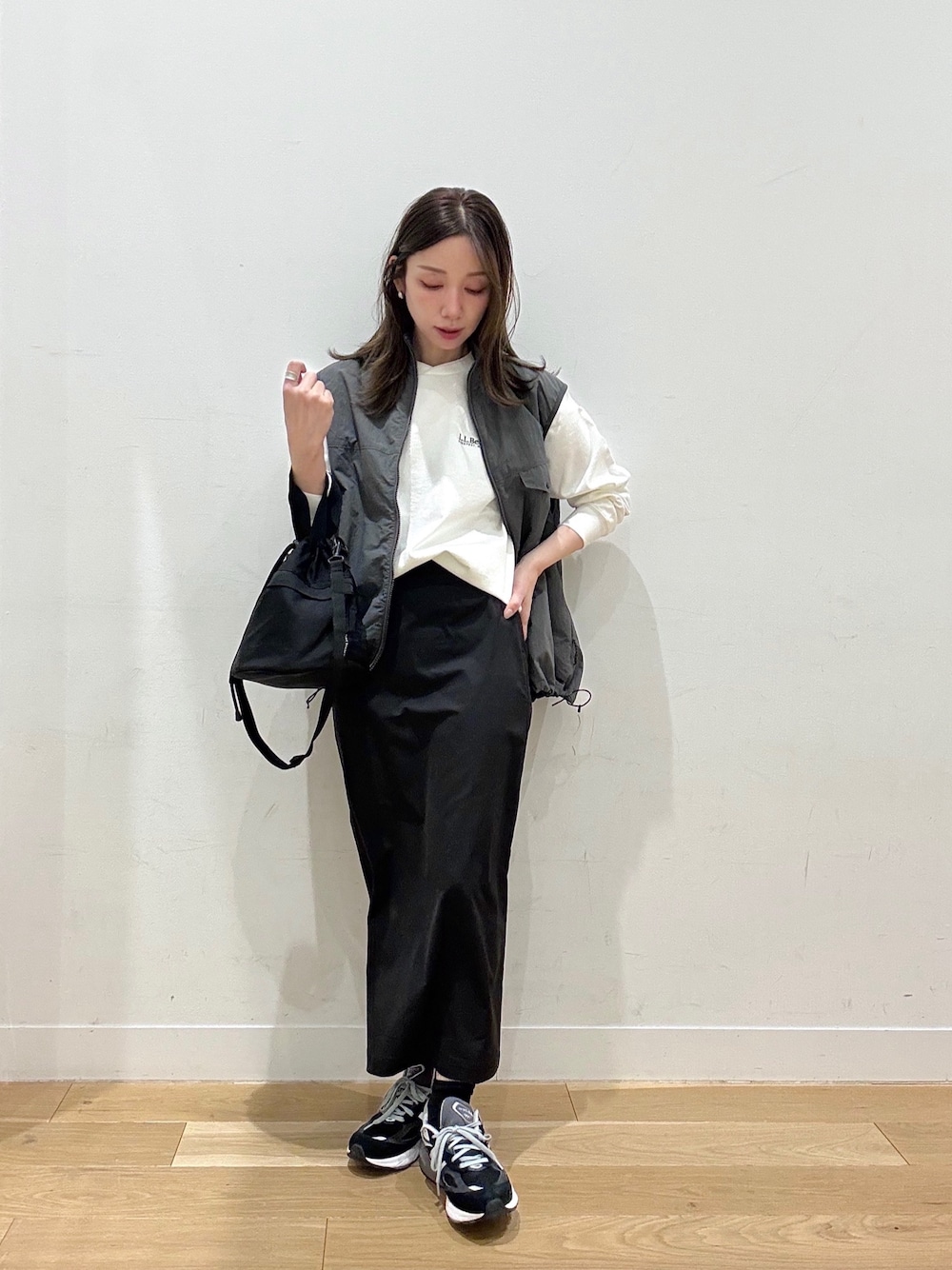 ブラック系のショルダーバッグ、ブラック系のスカート、グレー系のナイロンジャケットを着用したレディースの冬コーディネートの1枚目の写真