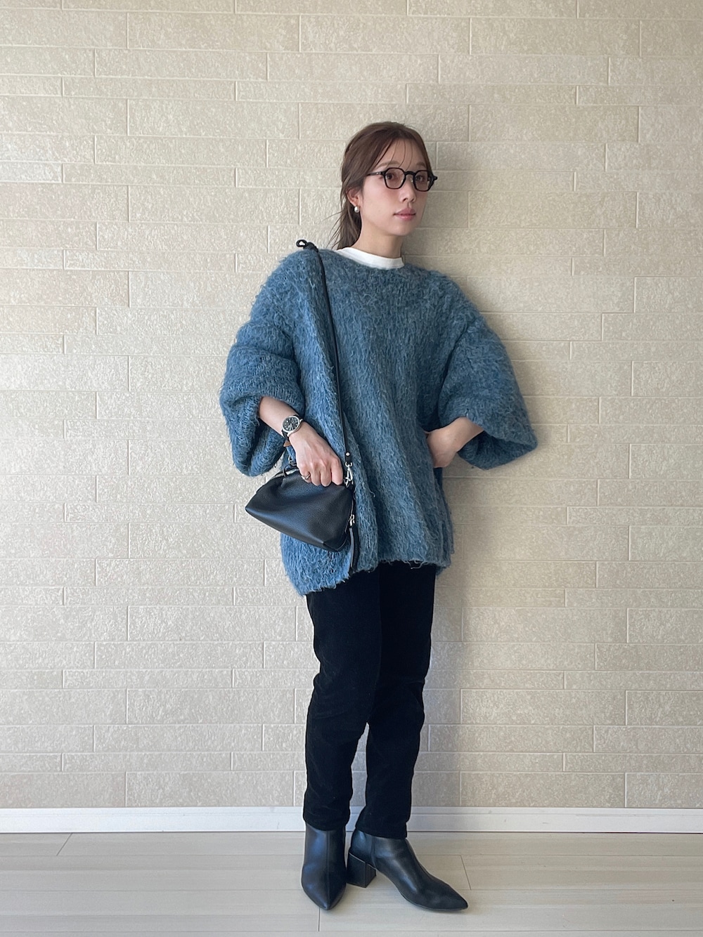 ブラック系のブーツ、ブルー系のニット/セーター、ブラック系のショルダーバッグを着用したレディースの冬コーディネートの1枚目の写真