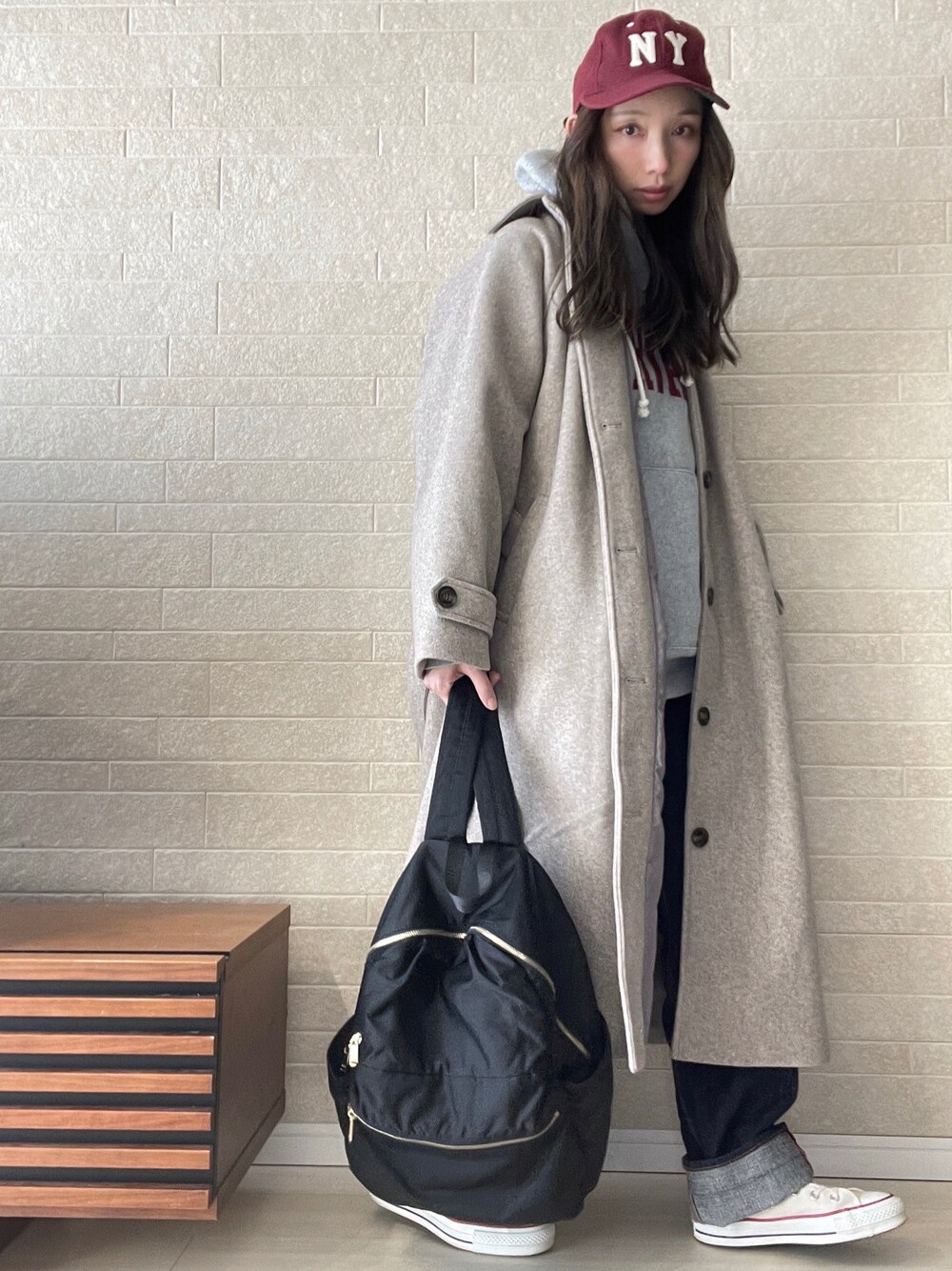 ベージュ系のステンカラーコート、グレー系のパーカー、ブルー系のデニムパンツを着用したレディースの秋コーディネートの1枚目の写真