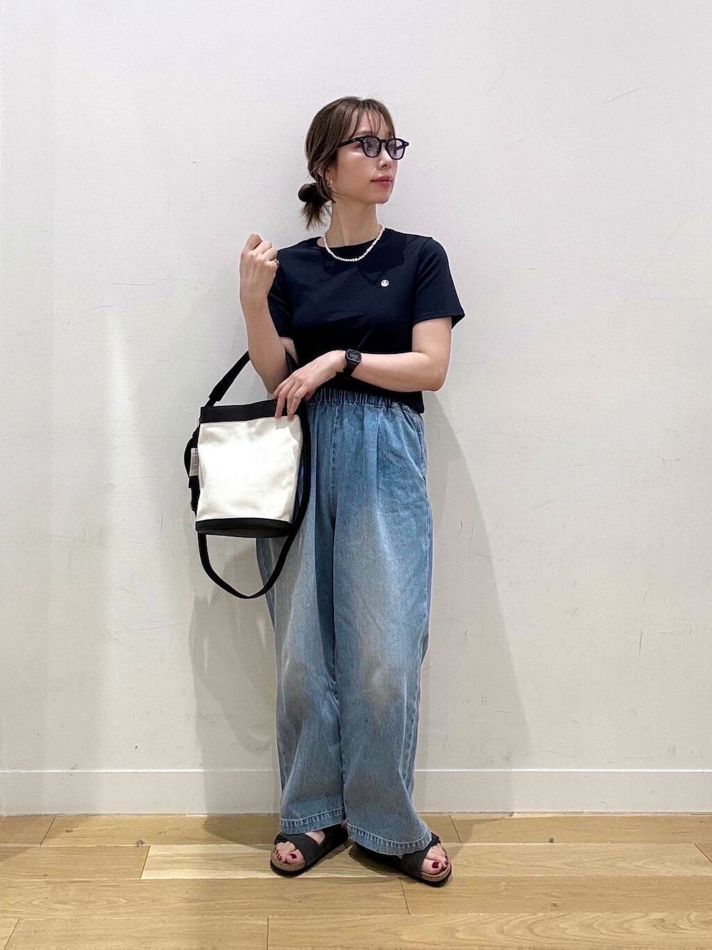 ブルー系のデニムパンツ、ブラック系のショルダーバッグ、グレー系のサンダルを着用したレディースの夏コーディネートの1枚目の写真