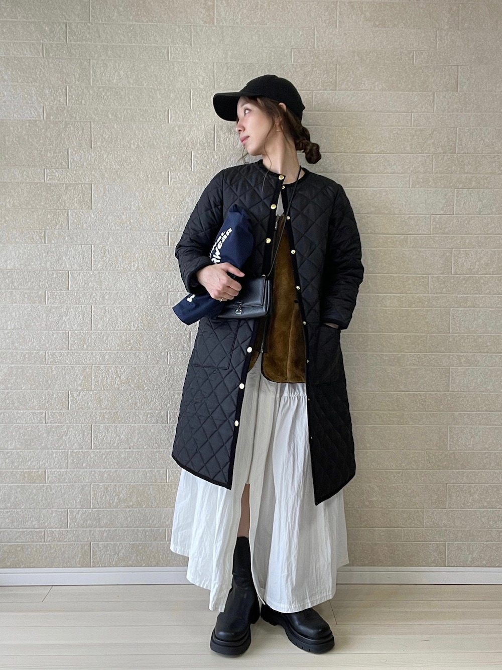 ブラック系のその他アウター、ブルー系のトートバッグ、ブラウン系のベストを着用したレディースの冬コーディネートの1枚目の写真