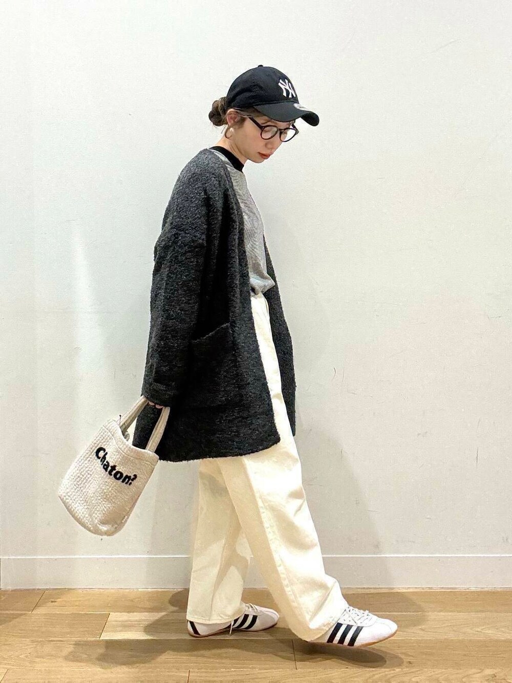 グレー系のカーディガン/ボレロ、ホワイト系のデニムパンツ、グレー系のトートバッグを着用したレディースの冬コーディネートの1枚目の写真