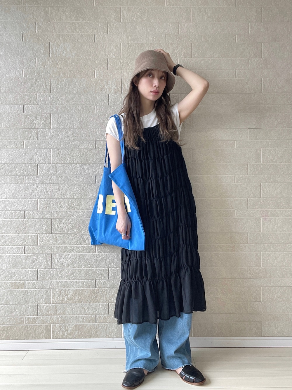ブラック系のワンピース、ブルー系のトートバッグ、ブルー系のデニムパンツを着用したレディースの夏コーディネートの1枚目の写真