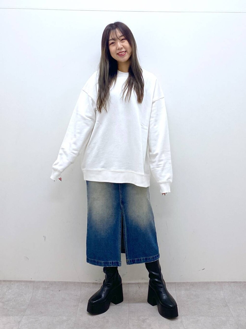 ブラック系のブーツ、ホワイト系のスウェット、ブルー系のスカートを着用したレディースの秋コーディネートの1枚目の写真