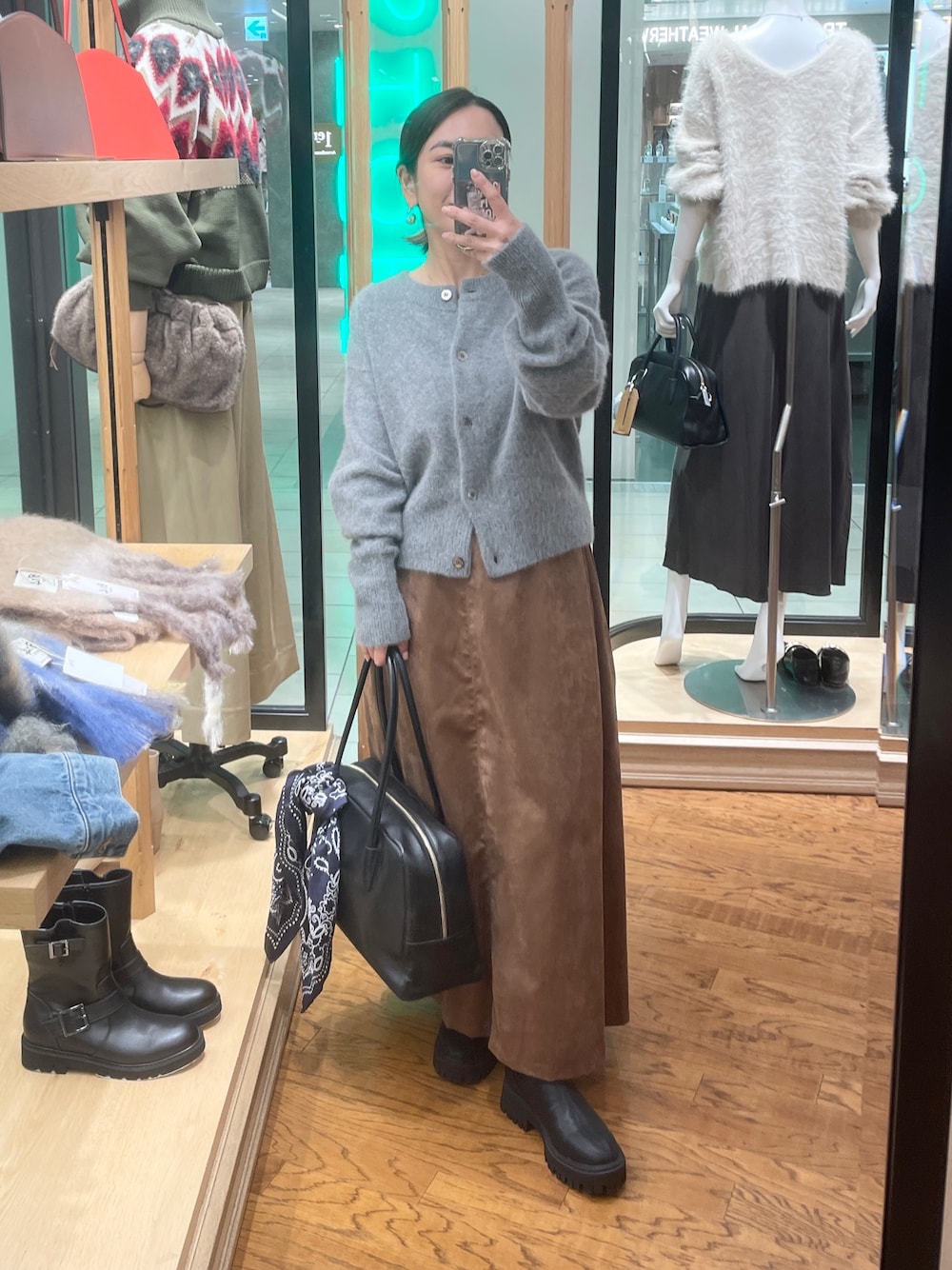 グレー系のカーディガン/ボレロ、イエロー系のスカート、ブラック系のブーツを着用したレディースの秋コーディネートの1枚目の写真