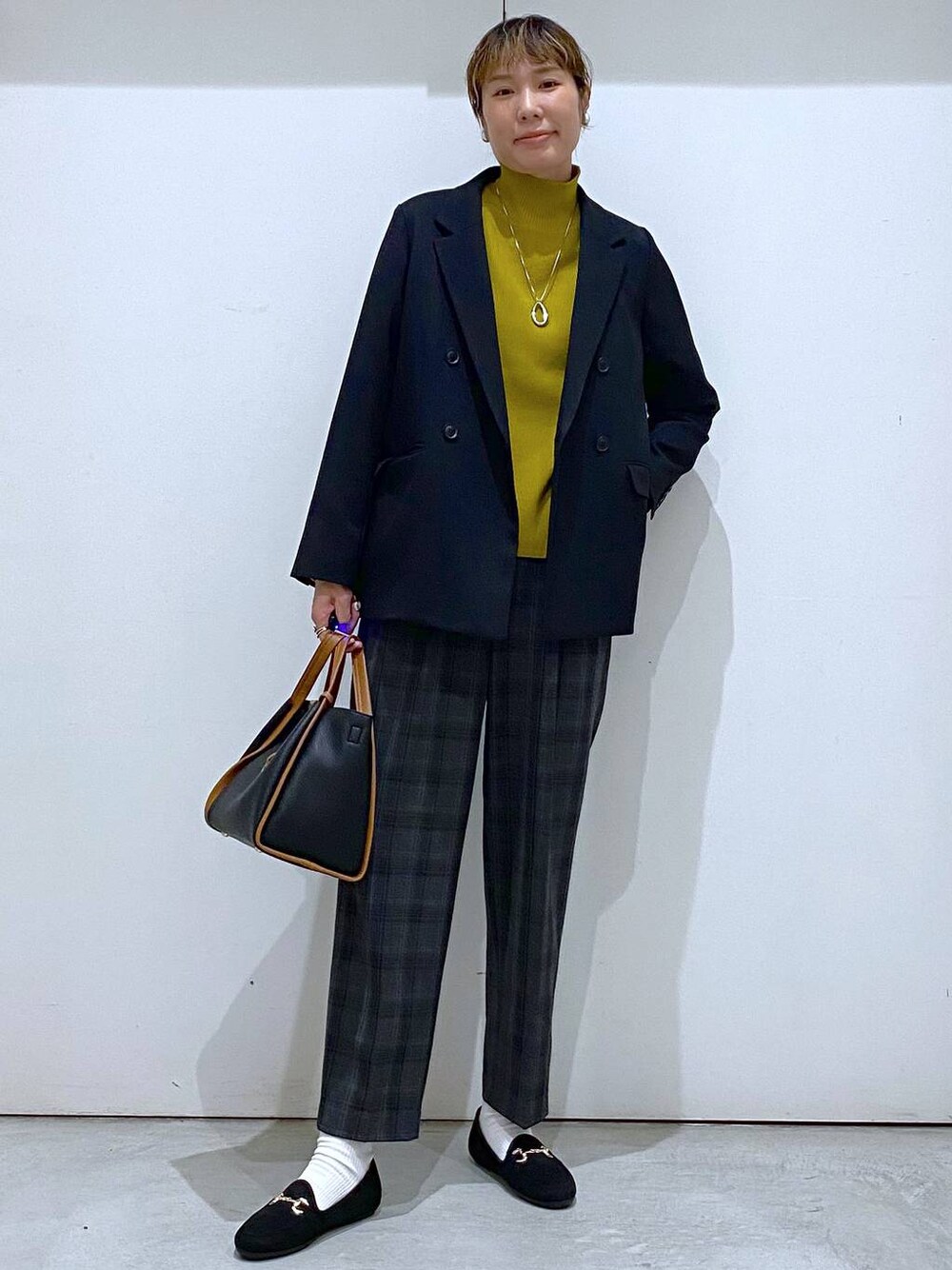 ブラック系のトートバッグ、イエロー系のニット/セーター、ブラック系のテーラードジャケットを着用したレディースの秋コーディネートの1枚目の写真