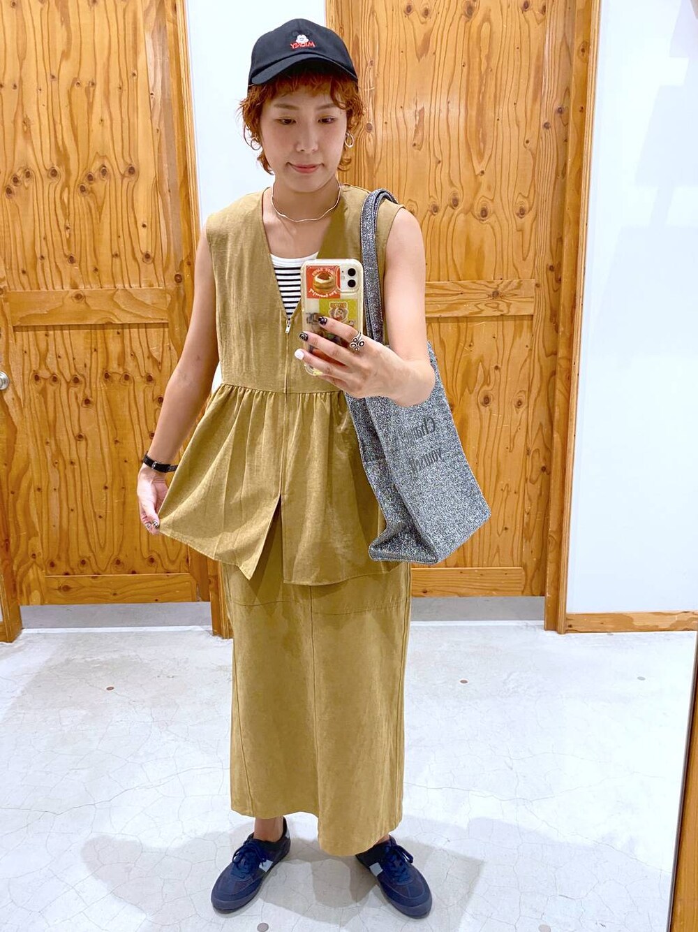 シルバー系のトートバッグ、ブルー系のスニーカー、イエロー系のベストを着用したレディースの夏コーディネートの1枚目の写真