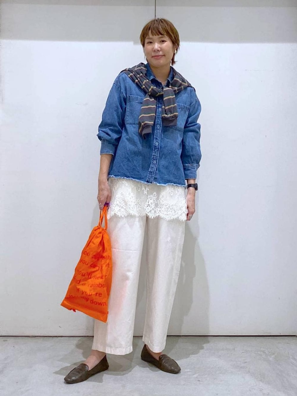 オレンジ系のバックパック/リュック、ブルー系のシャツ/ブラウス、グレー系のTシャツ/カットソーを着用したレディースの春コーディネートの1枚目の写真