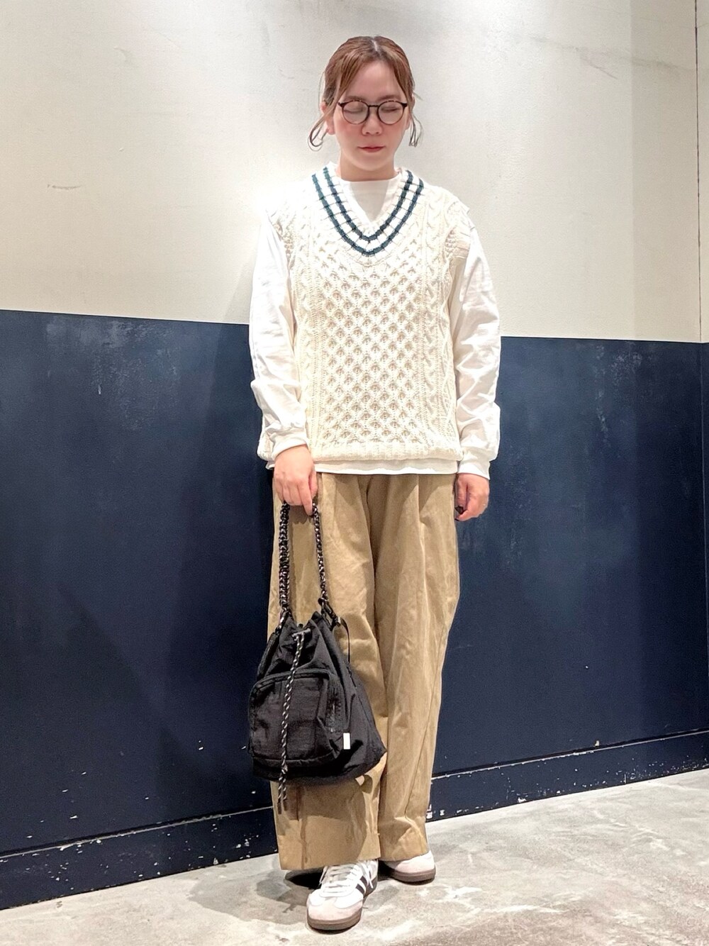 ベージュ系のデニムパンツ、ブラック系のトートバッグ、ホワイト系のベストを着用したレディースの秋コーディネートの1枚目の写真