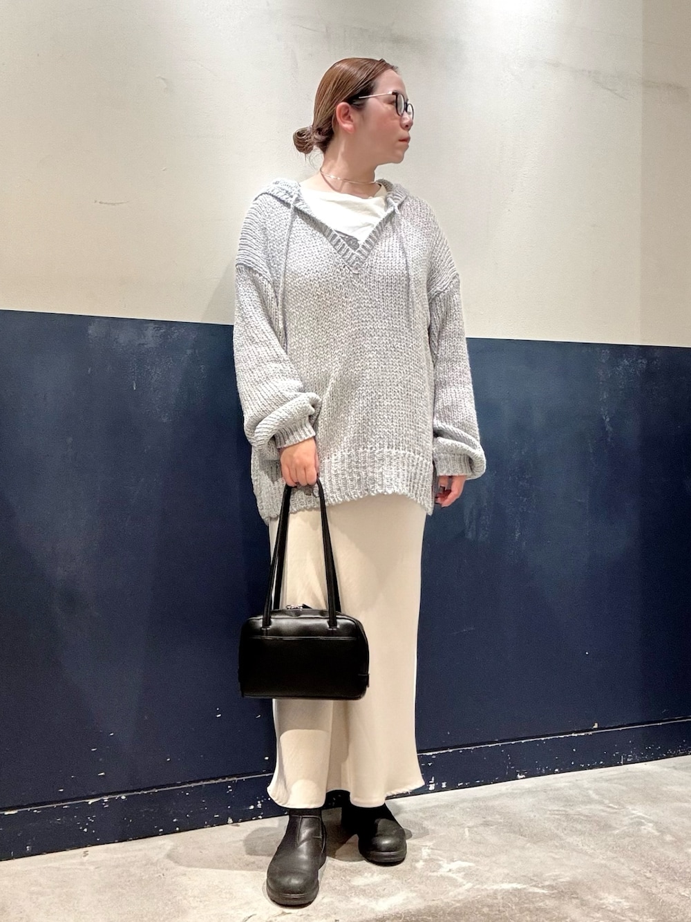 ブラック系のトートバッグ、ブルー系のニット/セーター、ホワイト系のTシャツ/カットソーを着用したレディースの秋コーディネートの1枚目の写真