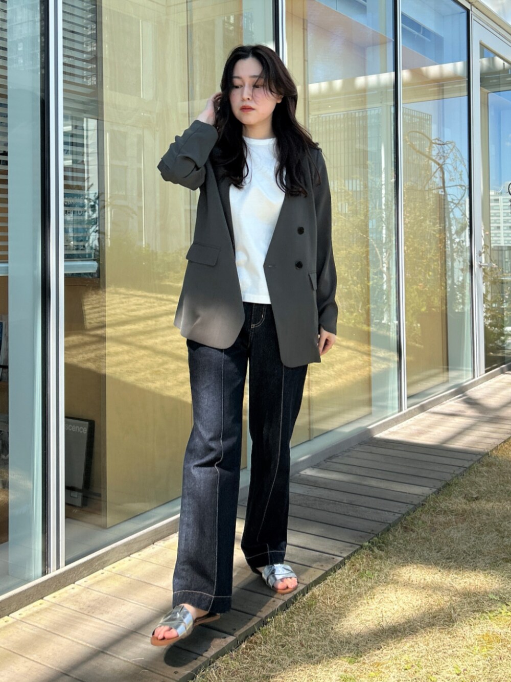 ブルー系のデニムパンツ、グレー系のノーカラージャケットを着用したレディースの春コーディネートの1枚目の写真