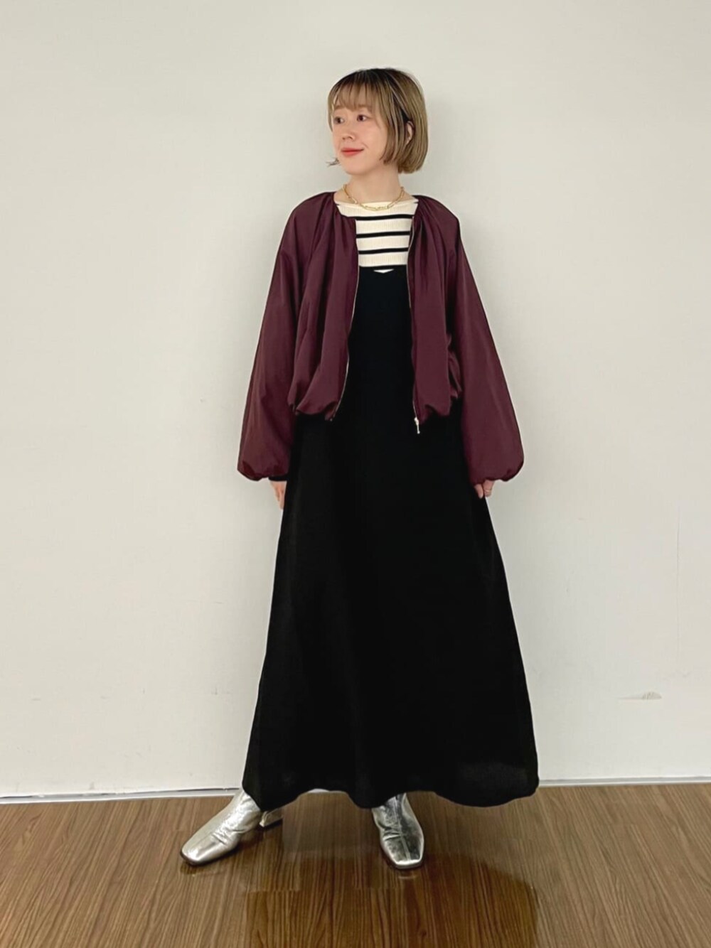 レッド系のブルゾン、ブラック系のワンピース、ベージュ系のニット/セーターを着用したレディースの秋コーディネートの1枚目の写真