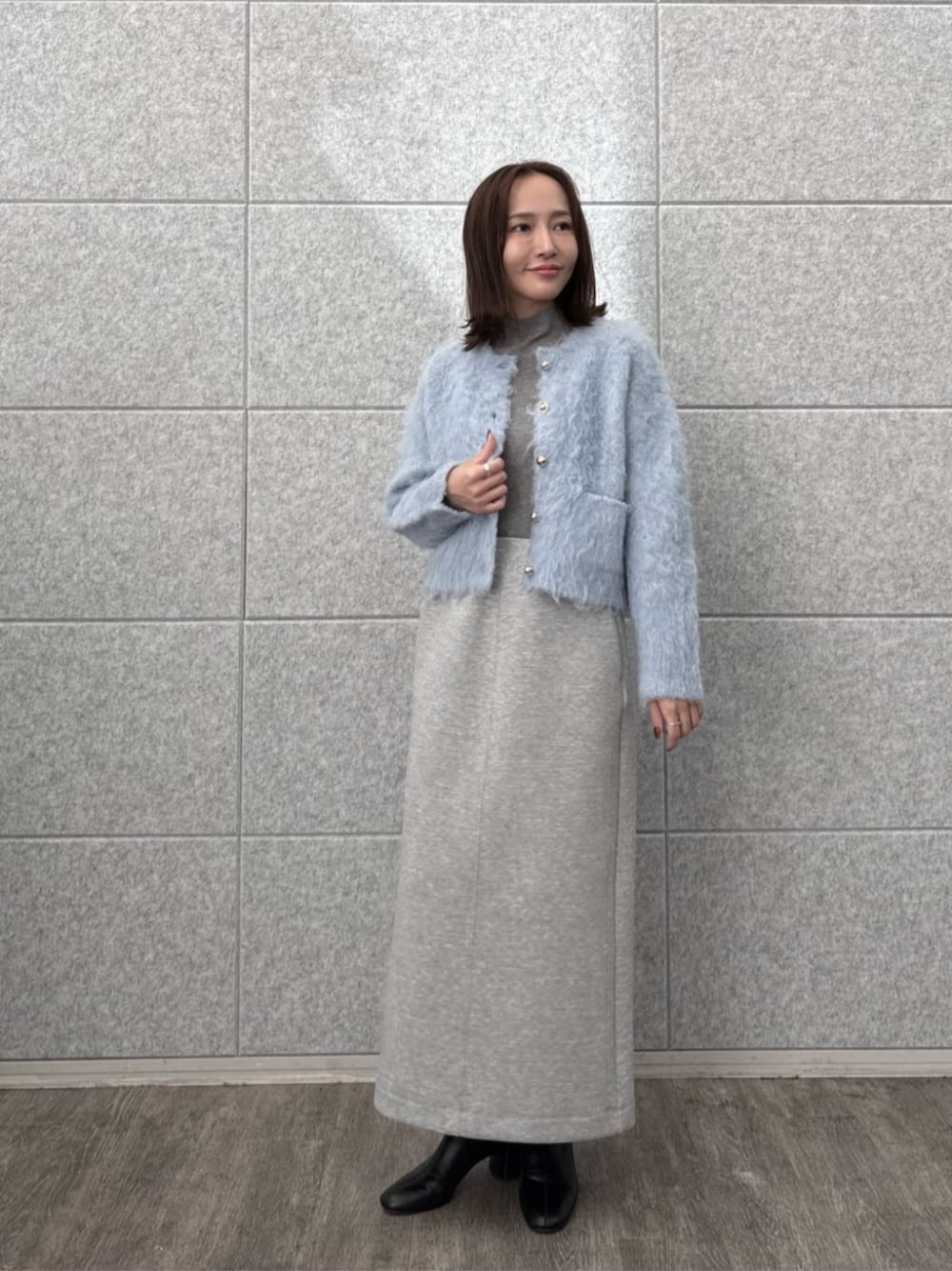 グレー系のスカート、グレー系のニット/セーター、ブルー系のカーディガン/ボレロを着用したレディースの秋コーディネートの1枚目の写真