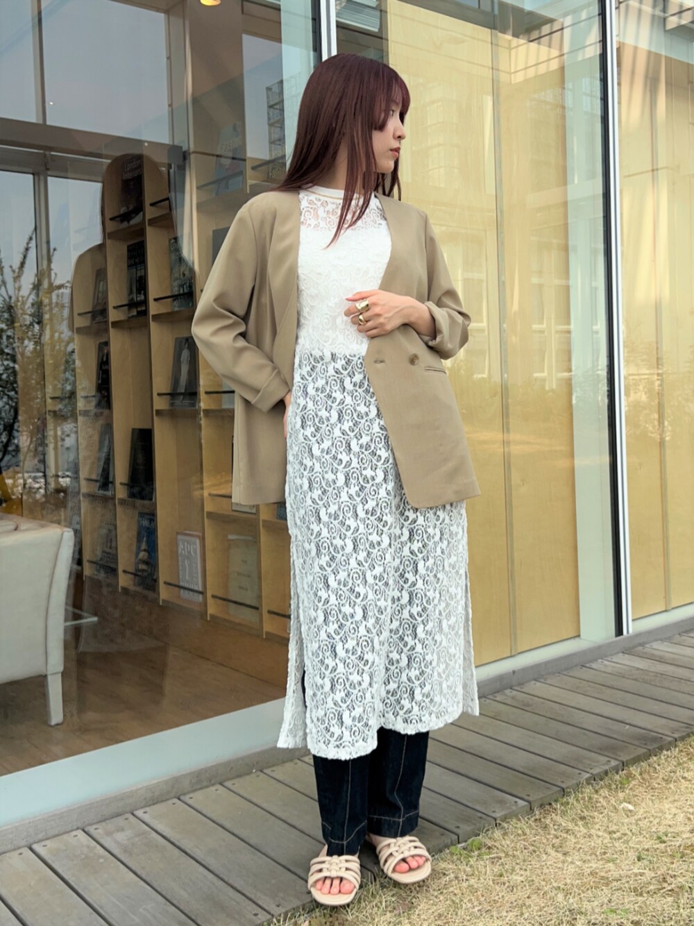 ブルー系のデニムパンツ、ベージュ系のノーカラージャケット、ホワイト系のタンクトップを着用したレディースの春コーディネートの1枚目の写真