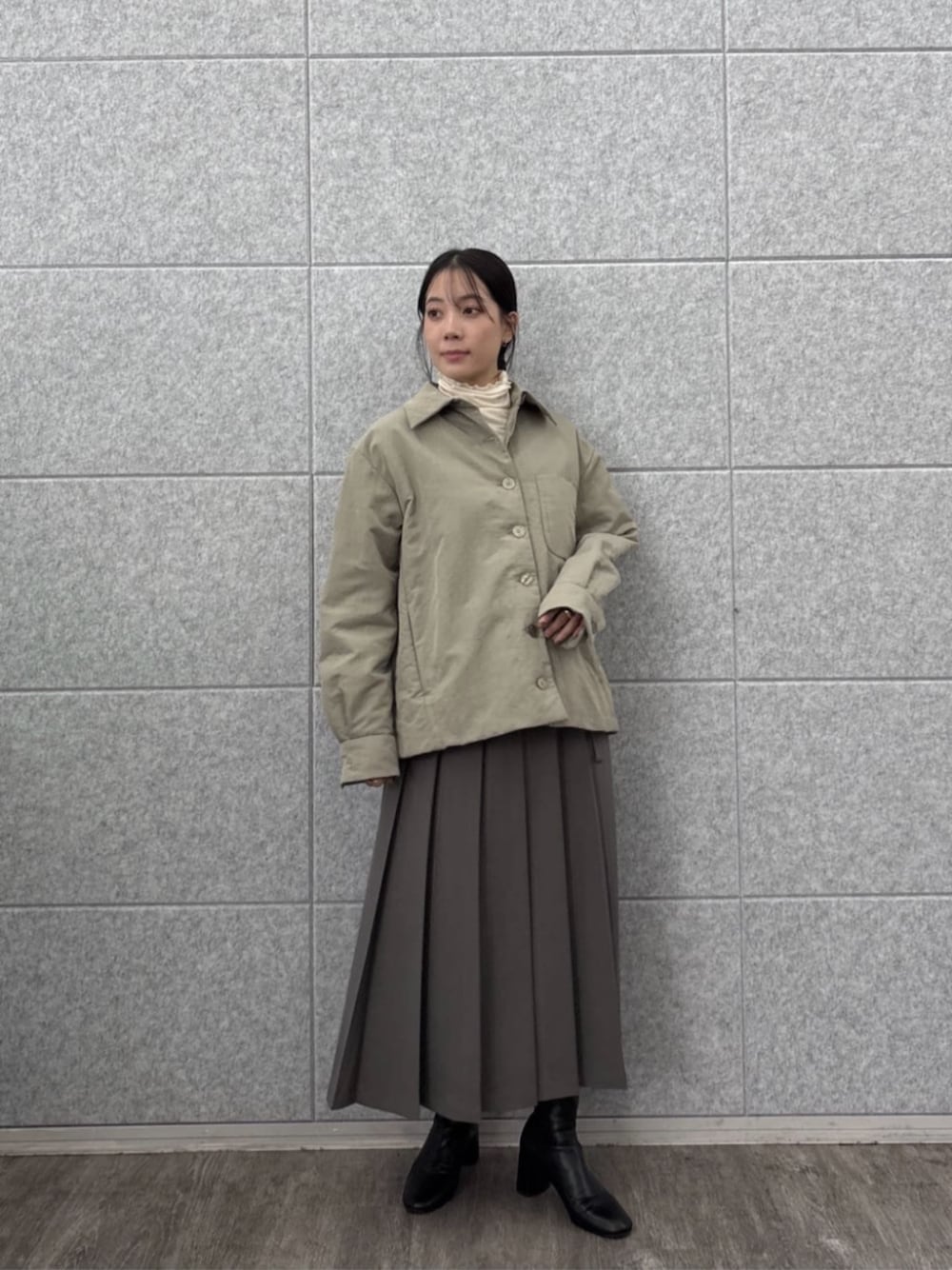 グレー系のスカート、ホワイト系のTシャツ/カットソー、グリーン系のブルゾンを着用したレディースの秋コーディネートの1枚目の写真