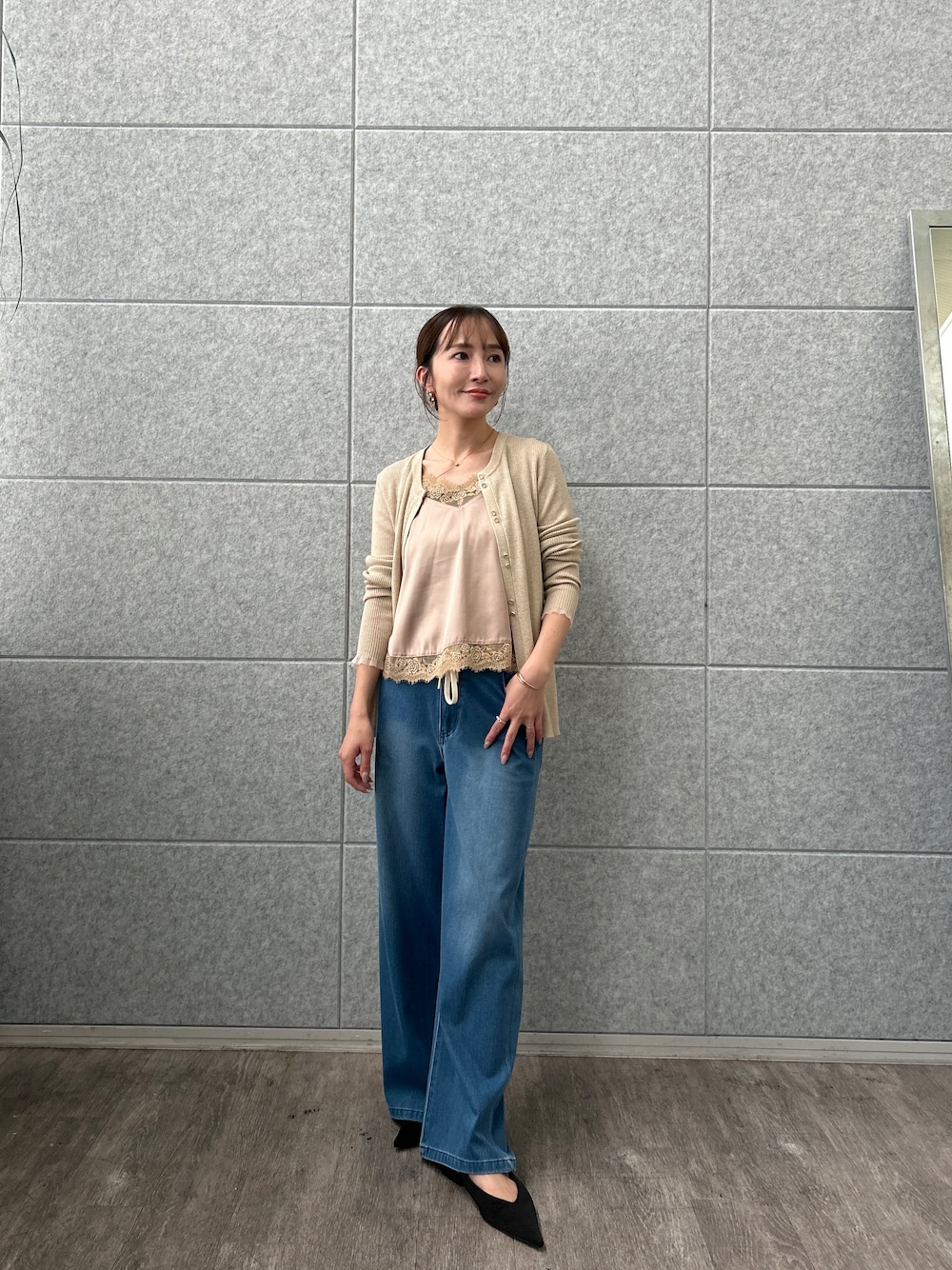 ベージュ系のカーディガン/ボレロ、ベージュ系のタンクトップ、ブルー系のデニムパンツを着用したレディースの秋コーディネートの1枚目の写真