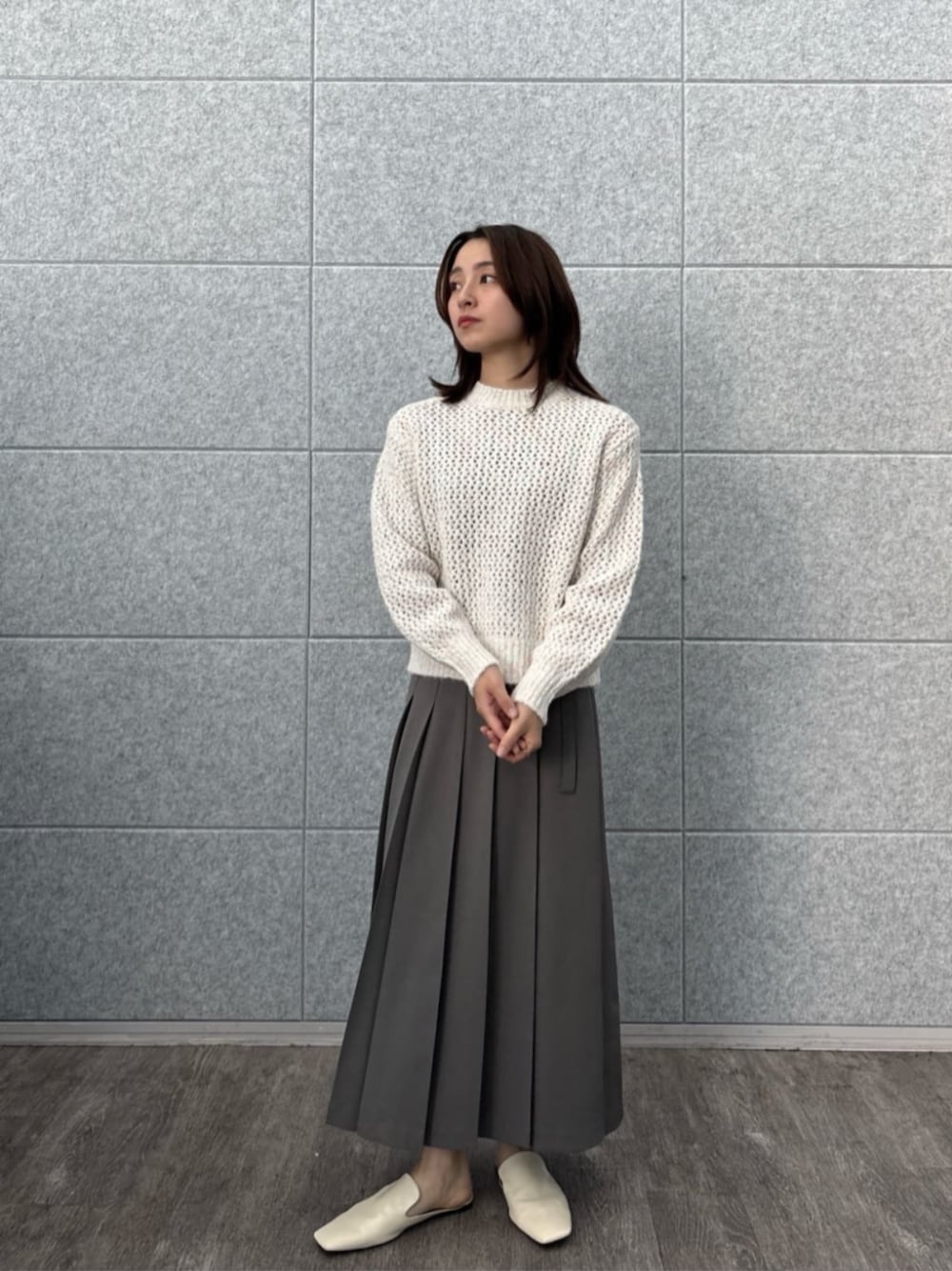 グレー系のスカート、ホワイト系のニット/セーターを着用したレディースの秋コーディネートの1枚目の写真
