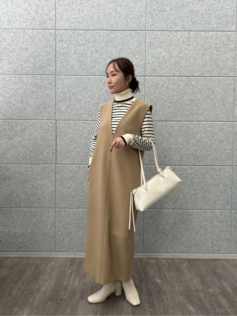 ベージュ系のワンピース、ホワイト系のニット/セーターを着用したレディースの冬コーディネートの1枚目の写真