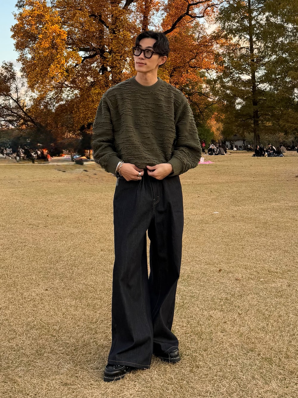 グリーン系のニット/セーター、ブルー系のデニムパンツ、ブラック系のドレスシューズを着用したメンズの冬コーディネートの1枚目の写真