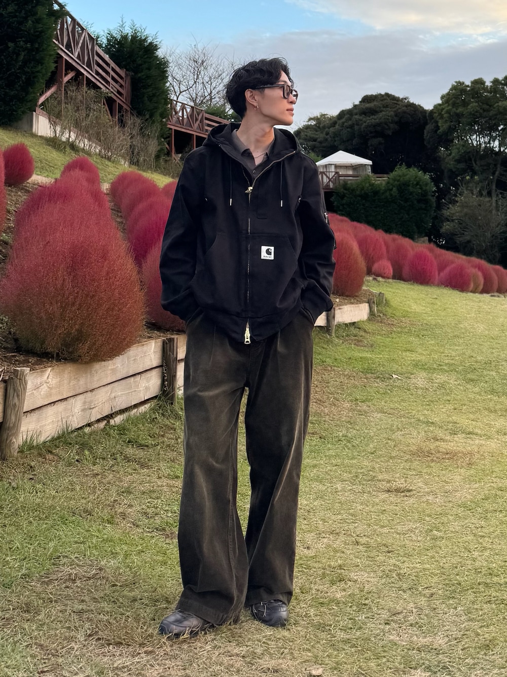 ブラック系のブルゾン、グリーン系のスラックス、ブラック系のスニーカーを着用したメンズの秋コーディネートの1枚目の写真