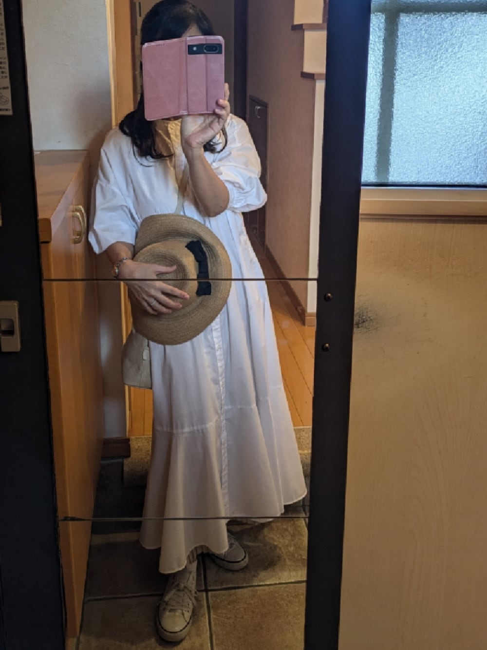 ホワイト系のシャツワンピース、ベージュ系のハットを着用したレディースの秋コーディネートの1枚目の写真