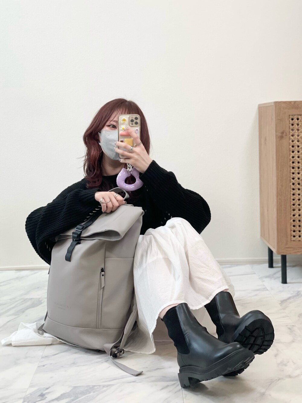 ブラック系のニット/セーター、ホワイト系のスカート、グレー系のバックパック/リュックを着用したレディースの秋コーディネートの1枚目の写真