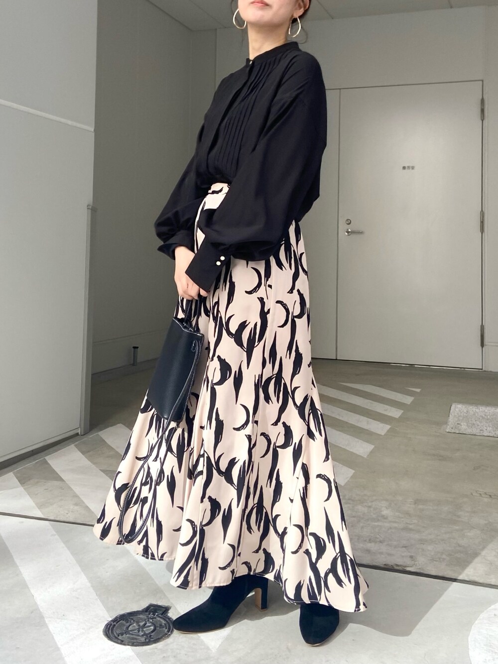 ブラック系のショルダーバッグ、ホワイト系のシャツ/ブラウス、ベージュ系のスカートを着用したレディースの冬コーディネートの2枚目の写真