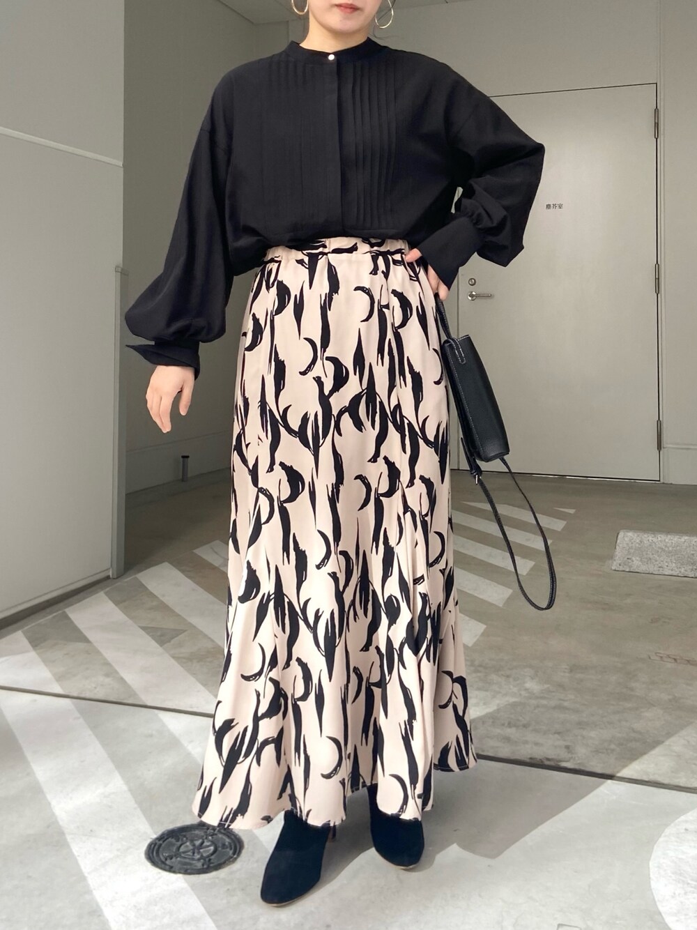 ブラック系のショルダーバッグ、ホワイト系のシャツ/ブラウス、ベージュ系のスカートを着用したレディースの冬コーディネートの3枚目の写真