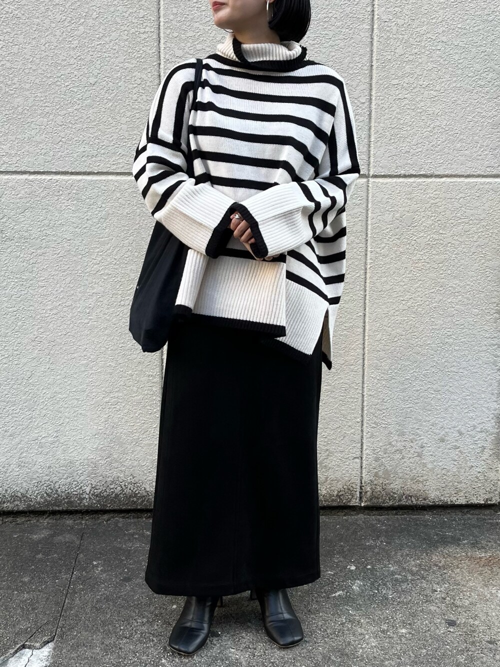 ホワイト系のニット/セーター、ブラック系のスカート、ブラック系のブーツを着用したレディースの冬コーディネートの3枚目の写真