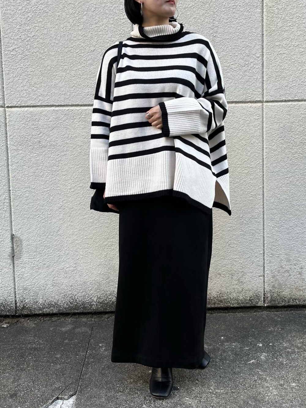 ホワイト系のニット/セーター、ブラック系のスカート、ブラック系のブーツを着用したレディースの冬コーディネートの2枚目の写真