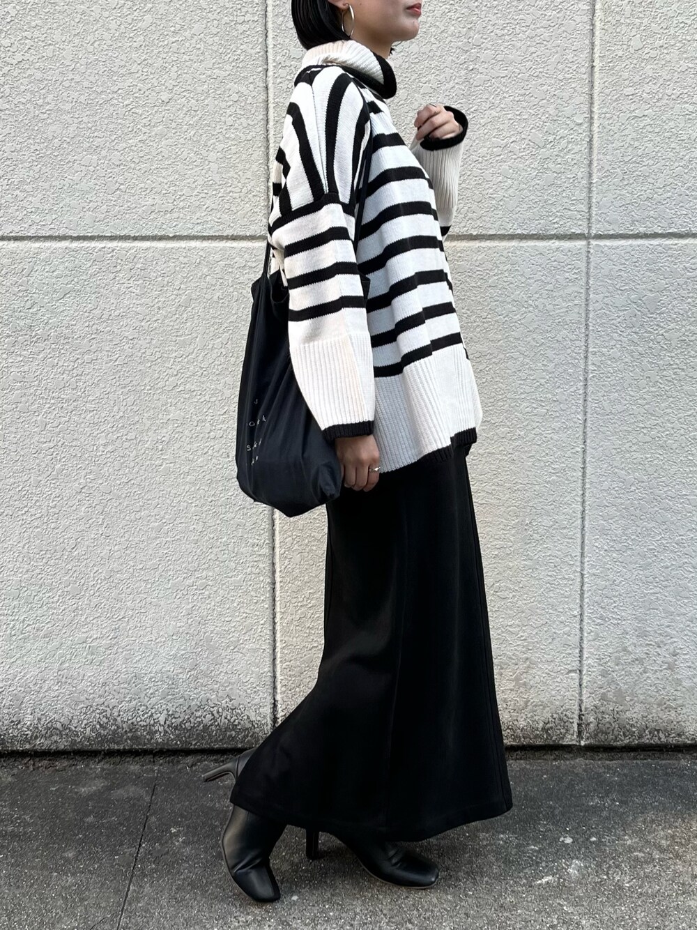 ホワイト系のニット/セーター、ブラック系のスカート、ブラック系のブーツを着用したレディースの冬コーディネートの4枚目の写真